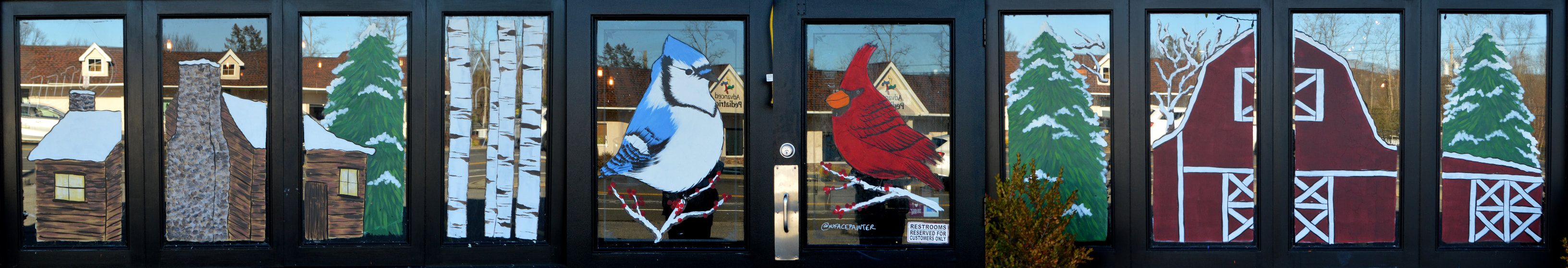Winter Window Painting at The Copper Still in Pomona, Rockland County, NY featuring a barn, a log cabin, a bluejay, and a cardinal