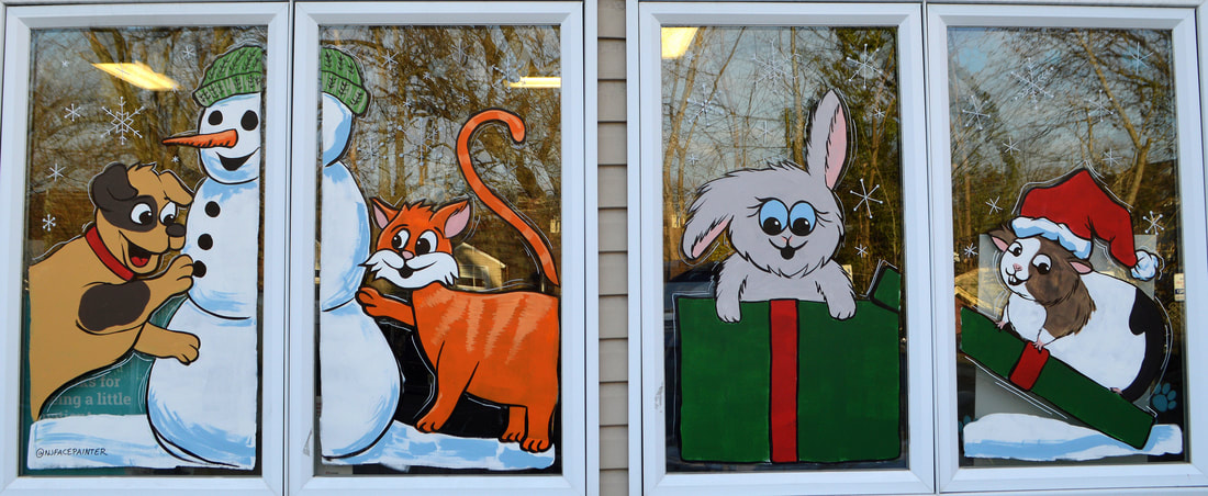 Christmas and Winter Window Painting at Maywood Veterinary Hospital in Maywood, Bergen County, NJ featuring a dog and cat building a snowman and a bunny and guinea pig gift