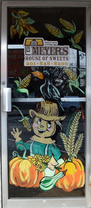 Fall Window Art at Meyer's House of Sweets in Wyckoff, Bergen County, NJ featuring a scarecrow, crow, pumpkins, wheat, and corn